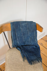 Close-up of vintage dark indigo hand-woven throw with subtle vertical stripes and fringed edge.