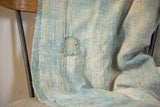 Light indigo hand-woven textile with visible mending and vertical stitched panel lines.