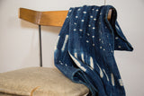 Collectible vintage indigo textile displaying irregular hand-dyed white patterns and soft texture.