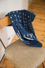 Folded indigo textile revealing hand woven texture with unique white patterns.