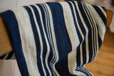 Collector hand-woven indigo throw showcasing textured blue and cream stripes.