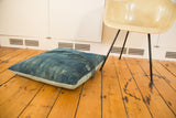 Textured indigo blue floor pillow with loose threads and light blue linen backing.