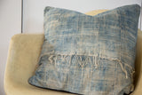 Upper right close-up of sun-faded African indigo textile with vertical stitching and loose threads.