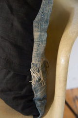 Close-up of vintage African Indigo pillow's faded blue textile and natural fringe.