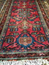 Distressed red antique Lilihan rug, featuring unique geometric design and white fringe.