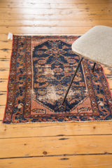 Distressed navy blue Malayer rug corner, faded dusty rose border, and short fringe.