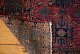 Curled corner of vintage Lilihan rug revealing hand-knotted foundation and vibrant raspberry red pile.