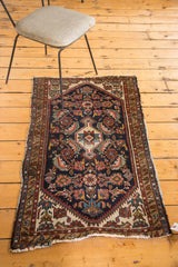 Distressed Malayer runner rug with Herati pattern, aged texture, partially under chair.