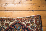 Distressed edge detail of vintage Malayer rug, geometric Herati pattern in navy, red, ivory.
