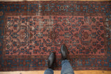 Distressed antique Malayer rug, showing worn texture, faded raspberry and indigo Herati motif.