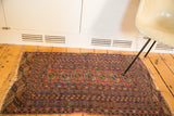 Distressed corner of a vintage Turkmen rug, showing frayed fringe and faded geometric gul motifs.