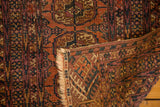 Hand-knotted foundation and distressed Bokhara guls on a folded vintage Turkmen rug.