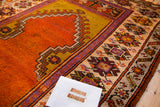 Tangerine orange and mustard yellow Ladik mehrab, geometric border, and color migration on vintage Oushak rug.