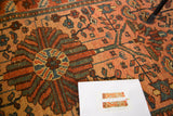 Detailed central flower and geometric tendrils in blue, green on dusty blush rose Malayer rug.