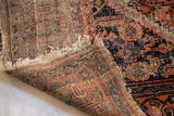 Distressed pile, frayed fringe, and visible hand-knotted foundation of an antique Malayer rug.
