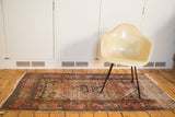 Antique distressed Malayer rug detail, featuring frayed right edge and worn madder red, blue Herati field.