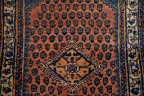 Corner of a diamond medallion on the terracotta field of a vintage hand-knotted Engelas rug.