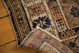 Folded antique Caucasian Kuba rug shows distressed geometric pile and unique mauve foundation.