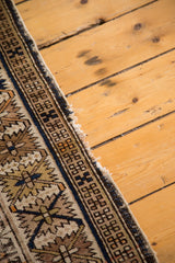 Tattered side edge of antique distressed Caucasian rug, showing indigo and brown geometric border.
