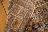 Distressed hand-knotted Kuba rug pile with geometric patterns in faded mauve, orange, indigo.