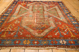 Distressed madder red field, sky blue border, and fragmented shield designs of an Antique Sewan Kazak rug.