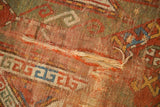 Close-up of an antique Sewan Kazak rug with visible tattered areas and geometric shield patterns.