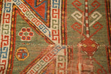 Distressed antique Sewan Kazak rug, with fragmented geometric patterns and visible tatter in madder red and olive.