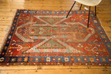 Distressed antique Sewan Kazak rug corner with fragmented red, green, and blue geometric motifs.
