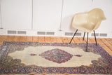 Vintage distressed Kerman rug corner with detailed floral milfleur border.