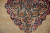 Distressed Kerman rug close-up: worn pile, scalloped floral motif in sky blue and cochineal red.