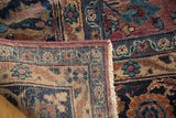 Folded corner of vintage Meshed carpet, detailing Safavid-inspired florals, fringe, and tightly woven reverse.