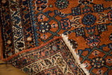 Vintage Hamadan rug folded corner, showing rust Herati pattern, reverse weave, and fringe.