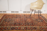 Antique distressed Baktiari rug's repeating multi-paneled design in softened cherry red, navy, and saffron.