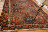 Detail of distressed Baktiari rug with multi-paneled cherry red, navy, saffron geometric designs.