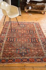 Distressed antique Baktiari rug edge, showcasing red and navy geometric crab border detail.