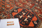 Distressed antique Baktiari rug with geometric navy blue and cherry red paneled patterns.