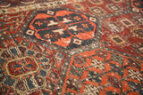 Textured worn pile of an antique distressed Baktiari rug in cherry red, navy, and saffron.