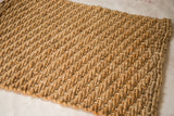 Textured close-up of the golden hand-braided natural fiber entrance mat.