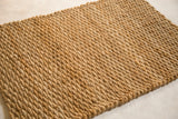 Close-up of the hand-braided golden natural fibers forming the durable entrance mat.