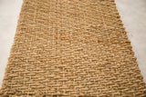 Close-up of the golden hand-woven texture on the natural fiber entrance mat.