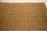 Coarse, hand-braided natural fiber texture in golden brown hues.