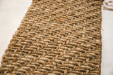 Textured hand-braided pattern of natural gold jute and sisal fibers on the mat.
