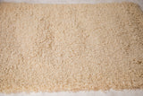 Close-up of plush light beige Moroccan shag texture and natural fringed edge.