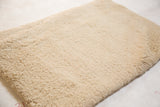 Plush hand woven texture of the natural ivory Moroccan shag bath mat.