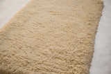 Textural detail of the hand-woven shag bath mat's plush, natural cream pile.