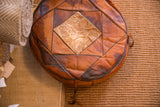 Vintage leather pouf close-up, with central deer hide and varied brown patchwork.