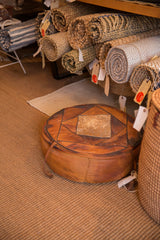 Vintage 1970s leather pouf featuring geometric brown panels and central worn hide.