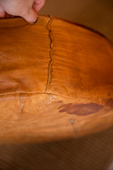 Aged cognac leather detail, highlighting the distinct seam and surface texture of the vintage pouf.