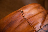 Vintage leather pouf with a distressed seam and rich brown, patinated texture.