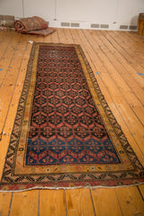 Secured hand-knotted fringe and geometric gold, black, and red border of an antique Malayer rug.